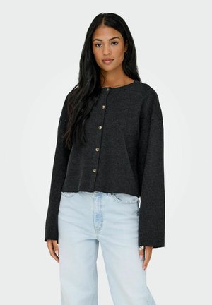 Pull en laine texturée, gris, court, à boutons. Il a un col rond et des manches longues avec de larges poignets.