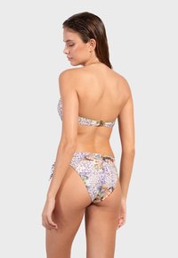 Bikini violet et crème avec un motif léopard, un haut bandeau avec un fermoir doré et un bas taille haute avec des accents à nouer.