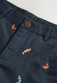 Shorts bleu marine avec broderie de poissons multicolores en orange, bleu et blanc, dotés d'une fermeture à bouton marron et d'un design plat à l'avant.