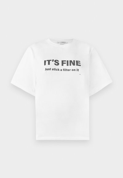 Άσπρο βαμβακερό T-shirt με κοντά μανίκια και στρογγυλή λαιμόκοψη. Διαθέτει τολμηρό μαύρο κείμενο: «ΕΙΝΑΙ ΕΝΤΑΞΕΙ Απλά βάλε ένα φίλτρο πάνω του.» Απλός σχεδιασμός.