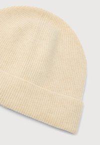 Gorro de punto beige con textura acanalada y dobladillo. Material suave y elástico con ligeras variaciones en el color.