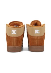 Hnědé semišové vysoké tenisky s hnědým koženým patním panelem, polstrovaným límcem a bílým logem DC na zadní straně. Gumová podrážka, šité detaily.