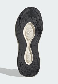 Podošva topánky s čiernym gumovým vzorom a bielymi akcentmi, so zakrivenými dizajnmi a textúrovanými ryhami pre trakciu a flexibilitu.