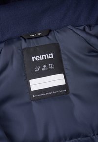 Marine stoffen label met "reima" merk; maat 104 en iconen die water, sneeuw en warmte aangeven. Label heeft een leeg gebied voor personalisatie.