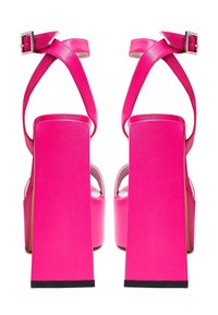 Sandales à talons hauts roses avec un talon carré, une sangle de cheville croisée et un accent à boucle. Texture en cuir lisse et brillant.