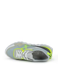 Zapatilla deportiva gris con material de malla y ante. Presenta cordones blancos, acentos en amarillo neón y un diseño de suela texturizada distintivo.