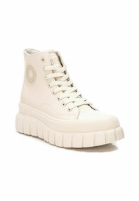 Zapatilla alta en color crema, fabricada en piel suave. Presenta un logotipo redondo, cordones planos y una suela gruesa con perfil estriado. Punta de goma texturizada.