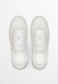 Sneakers grigio chiaro realizzati in pelle e camoscio, con punta tonda, dettagli perforati sulla parte anteriore e lacci bianchi.