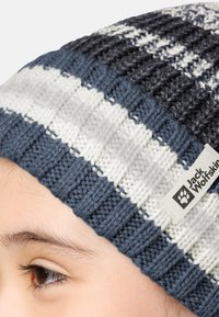 Cappello a maglia in blu navy, bianco e grigio con un motivo testurizzato. Include un'etichetta cucita con il logo "Jack Wolfskin".