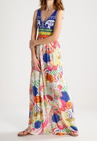 Robe longue avec corsage à motif bleu, encolure en V et jupe imprimée florale colorée. Présente un mélange d'accents rouges, roses et jaunes.