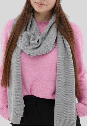 Écharpe grise en tricot drapée autour du cou, présentant un motif texturé. Portée avec un pull rose, créant un contraste de couleurs.