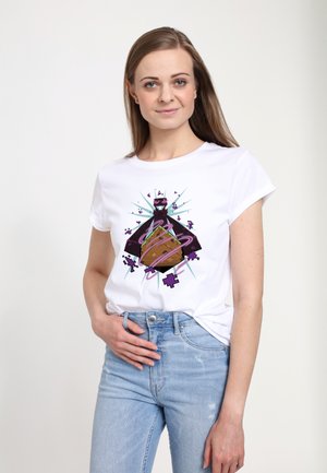 Kvinde iført en hvid t-shirt med en farverig grafik af et bjerg, lilla geometriske former og snoede lyserøde linjer, kombineret med lyseblå jeans.