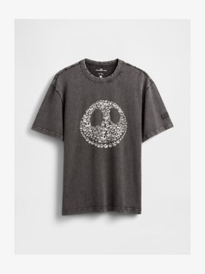 T-shirt grafica grigia in cotone, con un grande disegno circolare di una faccia sorridente con piccoli teschi, maniche corte e scollatura a girocollo.