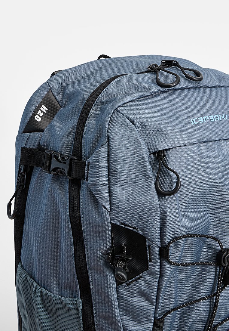 Blauer Stoffrucksack mit schwarzen Reißverschlüssen, verstellbaren Schnallen, Seitennetzfach und vorderem elastischen Kordelzug für den Außeneinsatz oder das Reisen.