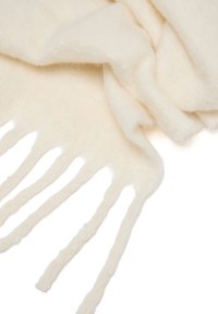 Sciarpa di lana morbida di colore crema con bordi frangiati, parzialmente piegata su uno sfondo bianco.