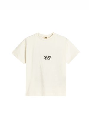Camiseta de algodón crema de manga corta, con estampado negro que dice "NYC" y texto "lo mejor de la ciudad" debajo. Cuello redondo, textura suave.