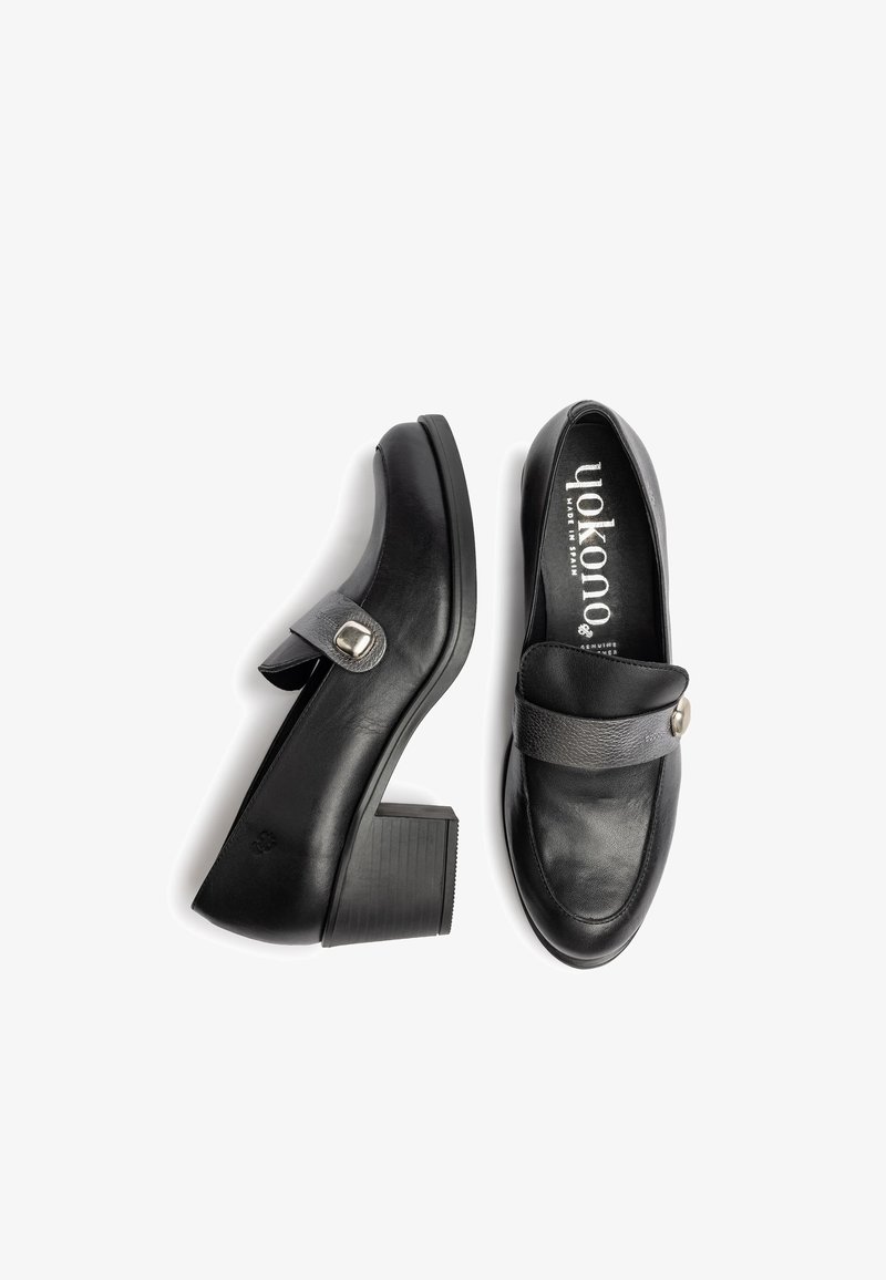 Black leather heeled loafers with a rounded toe, a wide strap across the instep, and a circular metal buckle detail. Textured block heel.