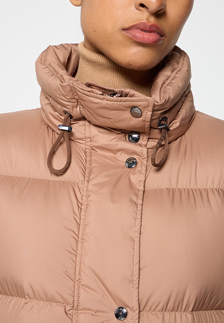 Beige gepolsterte Jacke mit hohem Kragen, verstellbaren Kordelzügen und glänzenden Knöpfen. Der Stoff hat eine glatte, weiche Textur mit gesteppten Details.