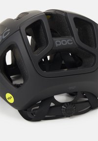 Casco de bicicleta negro con acabado mate, grandes recortes de ventilación, correas ajustables y etiqueta de tecnología MIPS en amarillo.