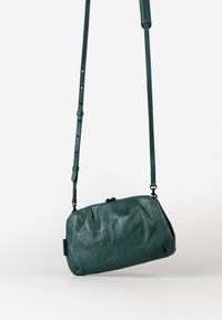 Türkise Leder-Crossbody-Tasche mit runder Form, geraffter Textur und verstellbarem Träger. Verfügt über einen Klappverschluss mit dekorativen Akzenten.