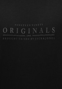 Μαύρο ύφασμα με ανάγλυφο κείμενο που γράφει «Nineteen Ninety Originals 1990 Brought to you by Jack & Jones» στο κέντρο.