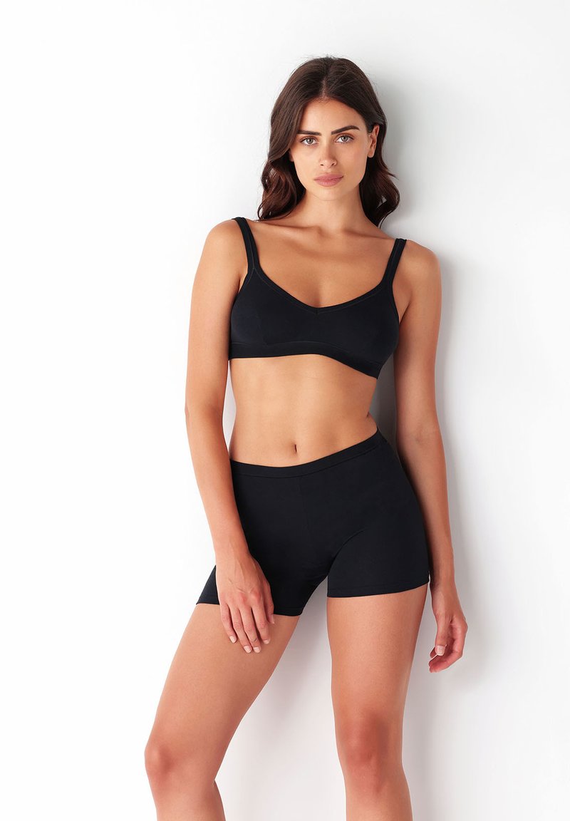 Zwarte bh en high-waisted shorts van gladde stof. De bh heeft een v-hals en verstelbare bandjes. De pasvorm is strak en minimalistisch.
