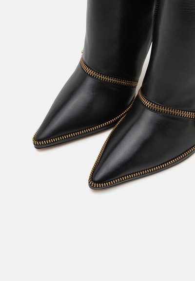 Zwarte leren laarzen met pointed toe en gouden ritsaccenten langs de naden, een gladde textuur en een strakke hoge kuitontwerp.