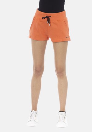 Shorts orange avec une taille ajustée et un cordon noir, comportant des poches latérales et le logo "just do it" dans une couleur contrastante.