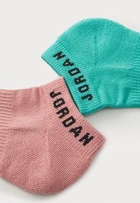 Calcetines de algodón en rosa y verde azulado, con textura acanalada. Impresiones en negro de "JORDAN" y "23" en los puños. Diseño atlético clásico.