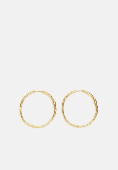 Cercei hoop din aur cu un design texturat, formă circulară și sistem de închidere cu clips pentru prindere. Dimensiunea este medie, potrivită pentru purtarea zilnică.