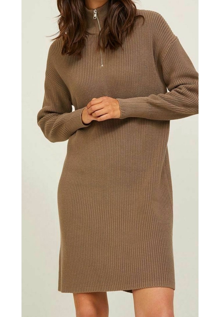 Abito maglione in marrone chiaro con colletto alto e chiusura con zip. Presenta una texture a coste e maniche lunghe, arrivando a metà coscia.