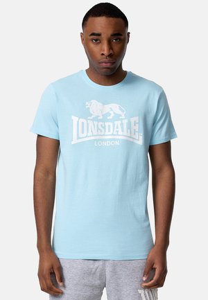 Svijetloplava pamučna majica s grafikom bijelog lava i tekstom "LONSDALE LONDON" u podebljanom, centriranom dizajnu. Kratki rukavi, okrugli izrez.