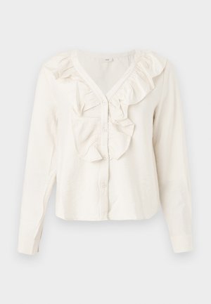 Hvit bluse med lange ermer og V-hals, frontknapper og volangkant rundt halslinjen og knappeområdet.