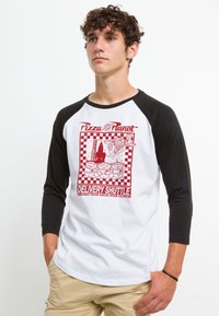 Hvid baseball t-shirt med sorte raglanærmer, der har et rødt grafik af "Pizza Planet" leveringsrumskib og tegneseriealiens på forsiden.