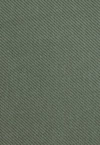 Texturovaná zelená tkanina s diagonálním vzorem, vyrobená z měkkého a odolného materiálu vhodného pro různé textilní aplikace.
