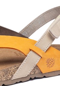 Sandales en daim avec un schéma de couleurs jaune et beige, dotées d'une semelle en liège, de brides texturées et d'un petit logo de coccinelle.