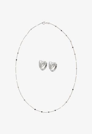 Collana a catena d'argento con piccole perle nere e argentate abbinata a orecchini a cerchio a forma di cuore in argento con trama testurizzata.
