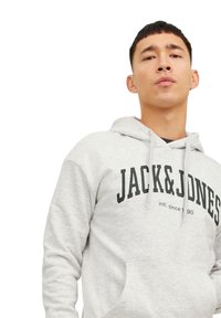 Lys grå hættejakke med en kængurulomme, der har et sort logo "JACK&JONES" på brystet og snore til justering af hætten.