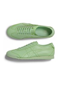 Světle zelené sportovní boty s hladkým koženým povrchem, kulatou špičkou, plochým zavazováním a texturovanou gumovou podrážkou s cik-cak vzorem.