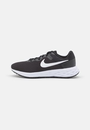 Chaussure de sport noire avec le swoosh blanc Nike et une semelle blanche rembourrée, vue de profil sur un fond clair uni.