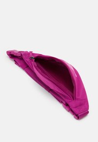 Magenta materiałowa nerka z otwartym suwakiem, siateczkowym wnętrzem i regulowanym paskiem z plastikową klamrą na białym tle.