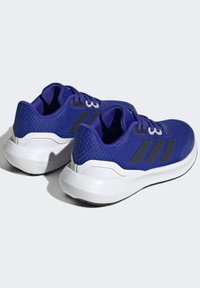Scarpe da ginnastica in tessuto viola con accenti neri, caratterizzate da una suola bianca ammortizzata e un marchio a tre strisce sui lati.