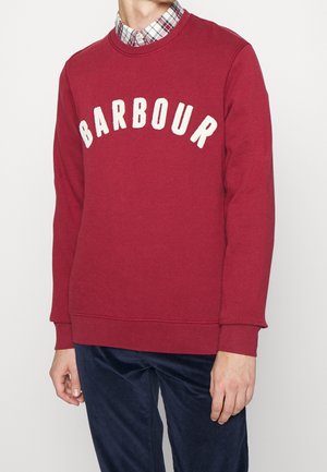 Bordeauxrode sweatshirt met "BARBOUR" in crème, ronde hals, geribbelde manchetten en zoom. Draagt over een geruit overhemd, wat een gelaagde stijl laat zien.