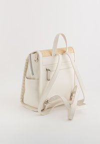 Mochila de cuero blanca con un panel superior de paja. Presenta un bolsillo con cremallera, un detalle lateral trenzado, correas ajustables y un bolsillo delantero deslizante.