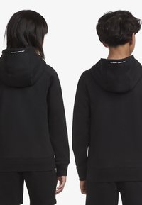 Μαύρες φούτερ με απαλή υφή, με λογότυπο στο πίσω μέ�ρος, ραγλαν μανίκια και ριμπ μανσέτες και στρίφωμα, φορεμένες από δύο άτομα από πίσω.