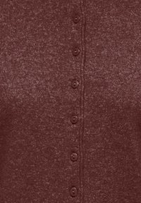 Gros plan sur un tissu tricoté bordeaux avec une rangée verticale de six petits boutons ronds bordeaux attachés.