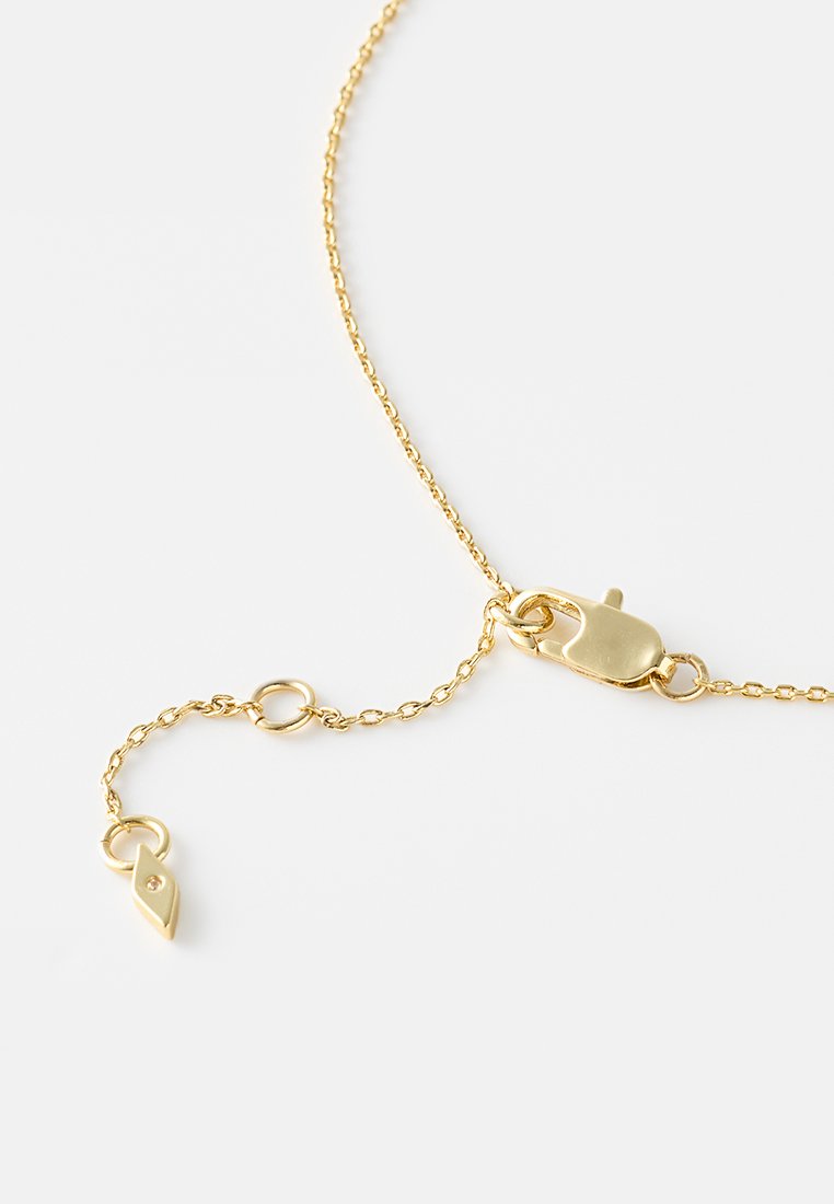 Bracciale in oro con chiusura a gabbiano e un ciondolo a forma di occhio con un piccolo accento in pietra. La catena presenta un design di anelli delicati.