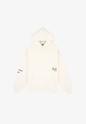 Hoodie oversize couleur crème avec une poche kangourou, des poignets côtelés et un texte brodé en bourgogne sur les manches et à l'avant.