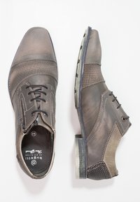 Chaussures en cuir gris présentant un mélange de surfaces lisses et texturées, un design à lacets, et un petit talon avec un accent décoratif sur le côté.
