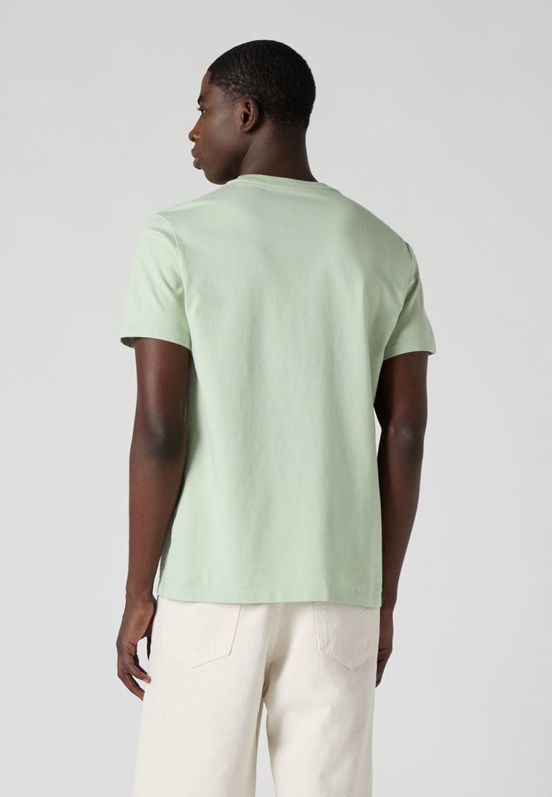 T-shirt en coton vert menthe avec un col rond, des manches courtes et une coupe décontractée. Présenté de dos sur un fond neutre.